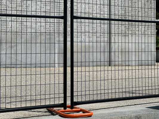 Black welded-wire temporary fence panels on a freestanding base