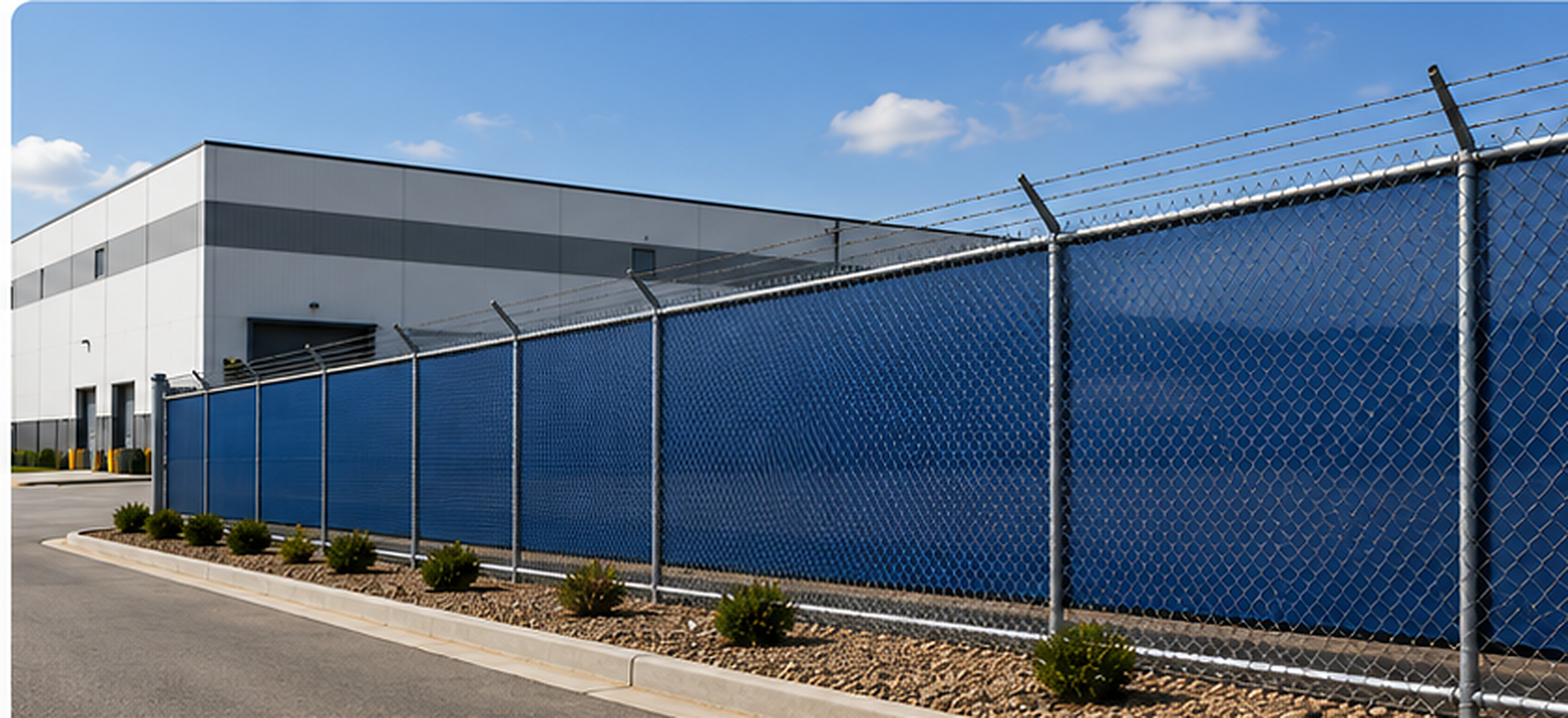 Commercial chain link fence with blue privacy windscreen at an industrial facility
