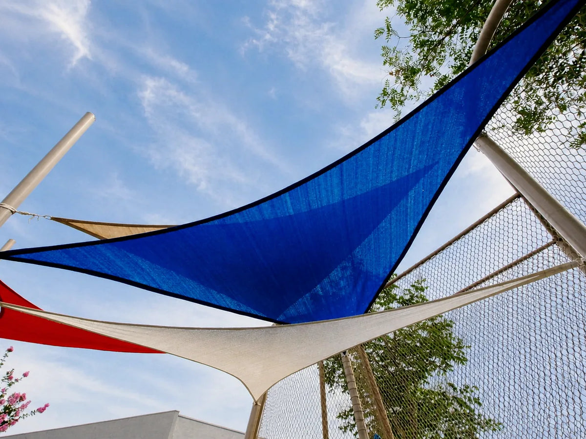 Overlapping blue, white, and red triangular shade sails attached to outdoor posts