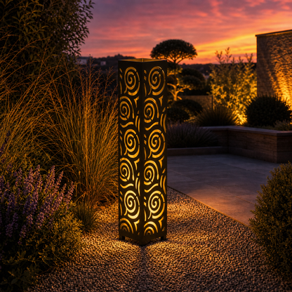 Design 057 outdoor decorative LED light column glowing at dusk in garden setting