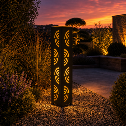 Design 121 outdoor decorative LED light column glowing at dusk in garden setting
